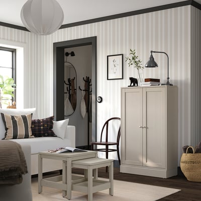 Modern bedroom with light grey striped walls, a white sofa, wooden cabinet, and a stylish pendant lamp.