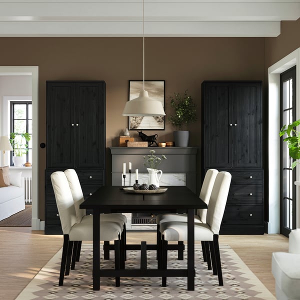 Modern dining room with black HAVSTA table and cabinets, four light chairs, symmetric placement, white pendant light, patterned rug, minimalist.