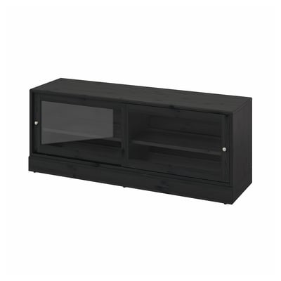A HAVSTA black tv cabinet with sliding glass doors, made of solid pine with a brushed finish, offering a rustic look and built-in cable management.