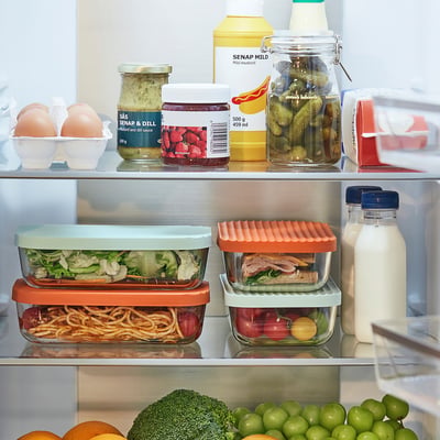 Fridge shelf with glass food containers storing leftovers, keeping food fresh and organised. Colourful lids stack containers efficiently.