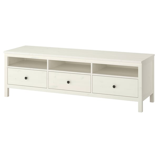 An ikea HEMNES white tv bench made of solid pine wood with three drawers and open compartments for storage.