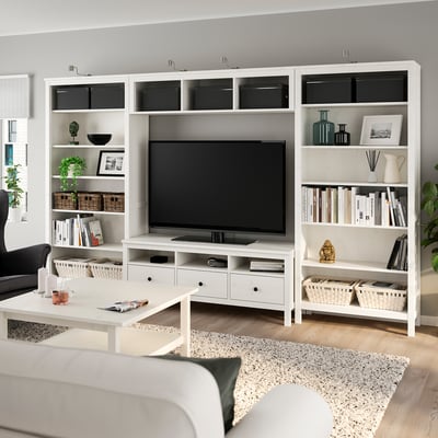 Modern living room with white HEMNES entertainment centre, tv, books, and decor. Cosy sofa on rug, plants, and coffee table.