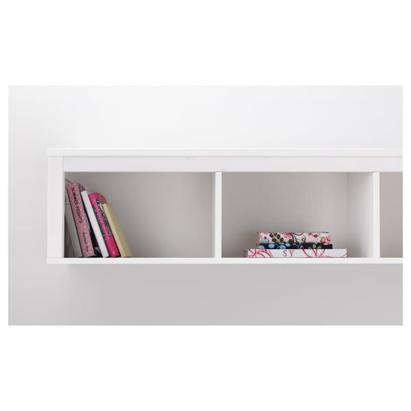 White wall shelf displaying colourful books and decorative boxes. Part of HEMNES series by IKEA.