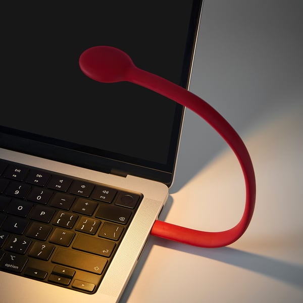 Red HÖSTULOTA lamp on laptop; slim, curved design.