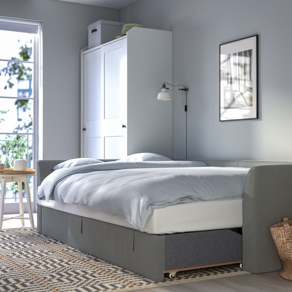A modern bedroom a versatile HOLMSUND sofa/bed with storage and a sleek design.