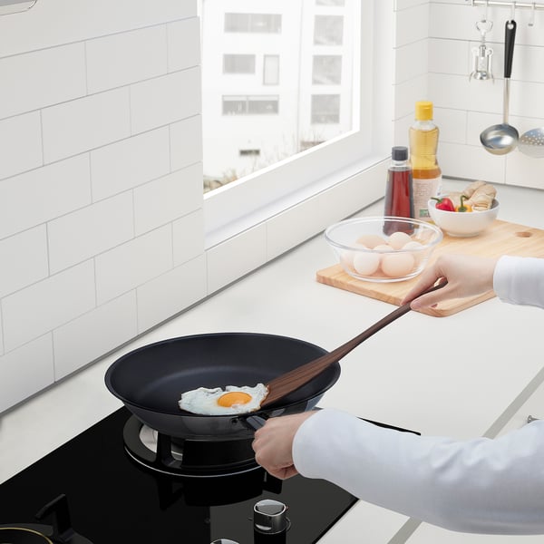 Cooking fried egg in pan with spatula. Kitchen counter has ingredients.