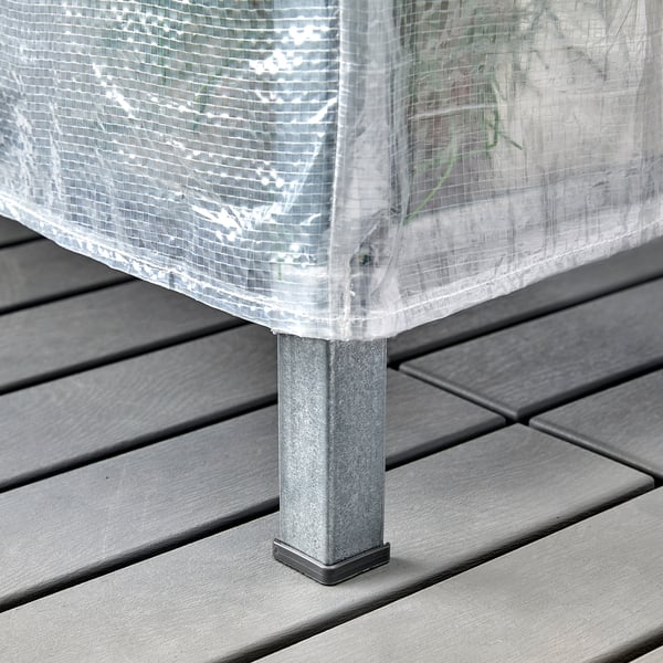 A storage unit on a deck with a transparent cover, designed to protect items from dust and create a small greenhouse.
