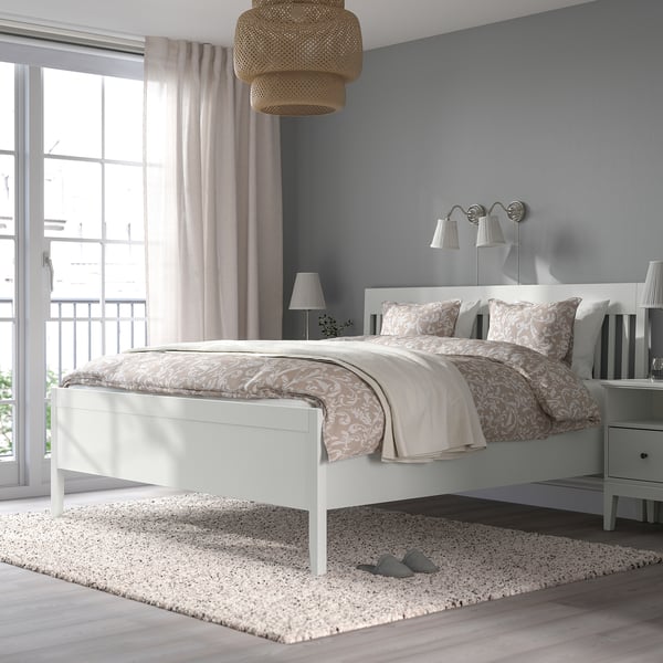 Modern white IDANÄS bed with tall headboard in cosy room. Blackout curtains and patterned bedding add subtle colour.