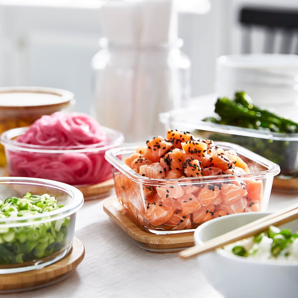 Clear containers with bamboo lids hold food. Tight lids preserve freshness. Lids double as coasters.