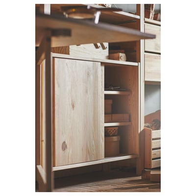 A wooden IVAR cabinet with light wood finish, sliding door, and storage baskets.