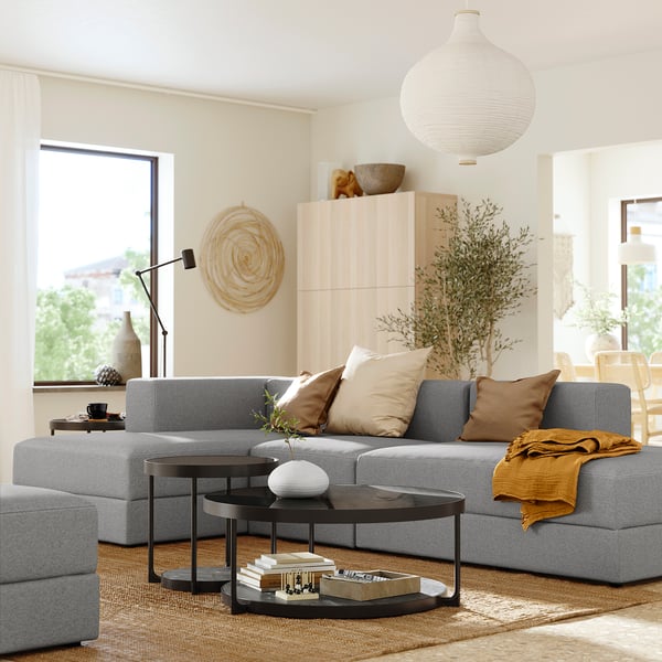 Modern living room with grey JÄTTEBO sofa, black coffee table, wooden cabinet, and large windows.