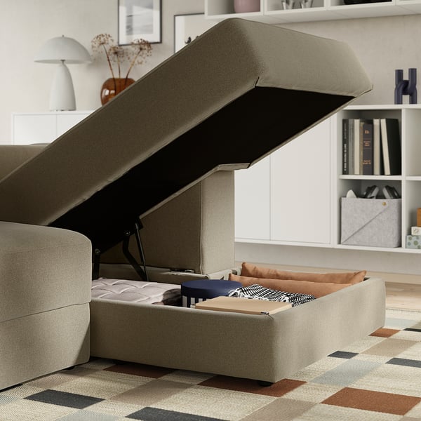 Modern sofa with open storage underneath, revealing cushions and items.