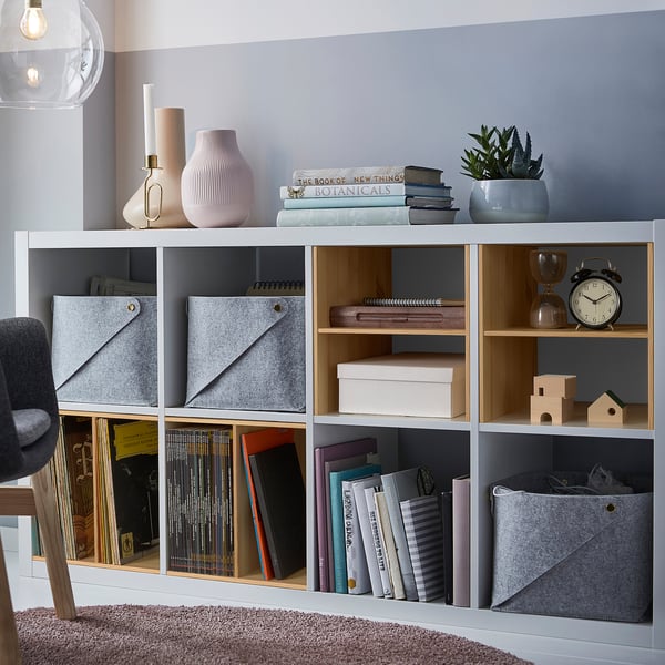 KALLAX shelves with pine inserts store books, decor. Grey, wooden, rectangular, organised. Larger than items stored.