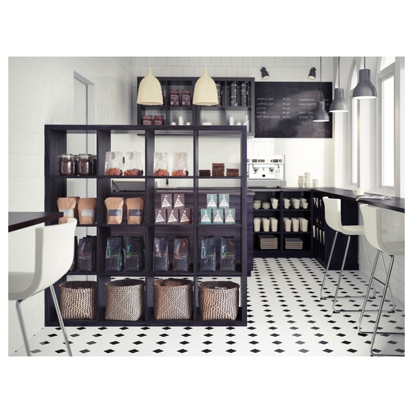 Modern coffee shop with black KALLAX shelves, white accents, pendant lights, and black and white tiled floor.