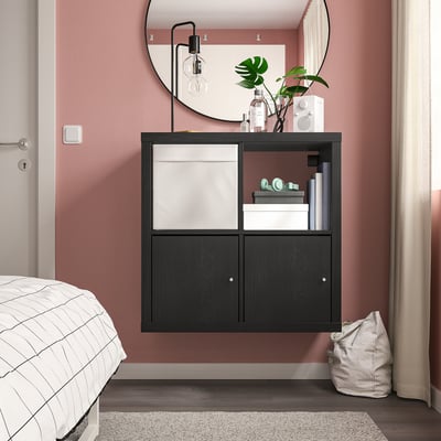 Modern bedroom with black KALLAX storage, books, decor, plant, mirror, and plaid bed.