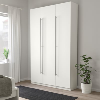 Modern white tall wardrobe with sleek silver handles, taller than plant and bed, minimalist design.