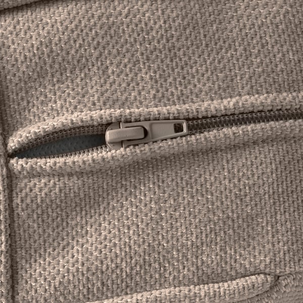 Close-up of a textured, light grey sofa with a partially opened zip, showcasing high-quality craftsmanship and durable stitching.