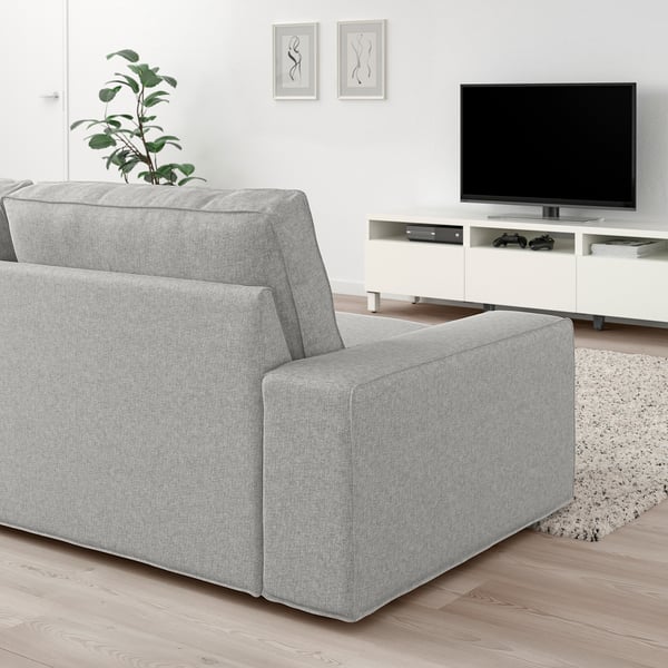 Modern living room with KIVIK sofa, tv, plant, & art. Sofa is large, grey, & plush.