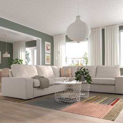 Living room with KIVIK sectional, coffee table, striped rug, large windows, green walls.