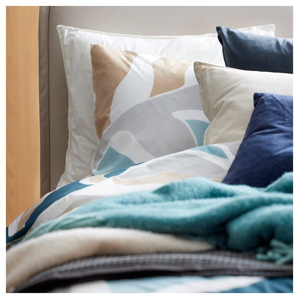 Bed with geometric-print pillowcases, blue and white, in soft fabric.