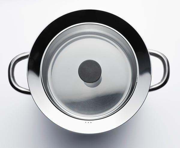Silver pot with clear glass lid, wide metal rim, steady handles.