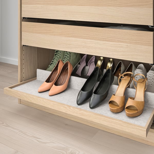 A wooden closet with a pull-out tray storing various shoes; a practical solution for organised footwear storage.