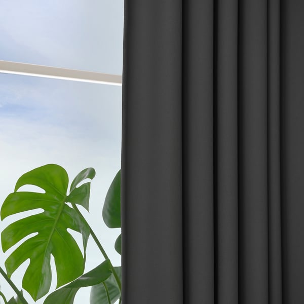Dark grey block-out curtains near plant.