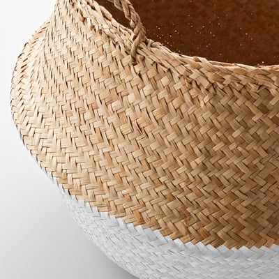 Handwoven seagrass basket with sturdy handles, partially dipped in white, resting on a brown surface.
