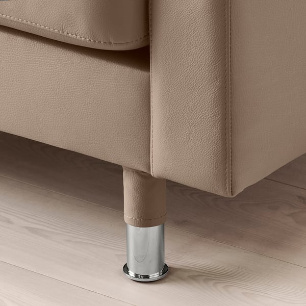 Close-up of a beige leather sofa. Chrome-plated metal leg, polished base, visible stitching. Modern, high-quality design.