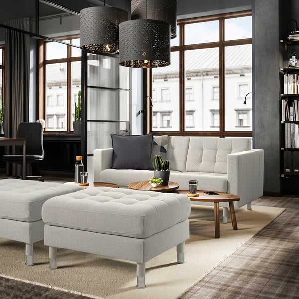 Modern living space with grey footstool, sofa, and lanterns.