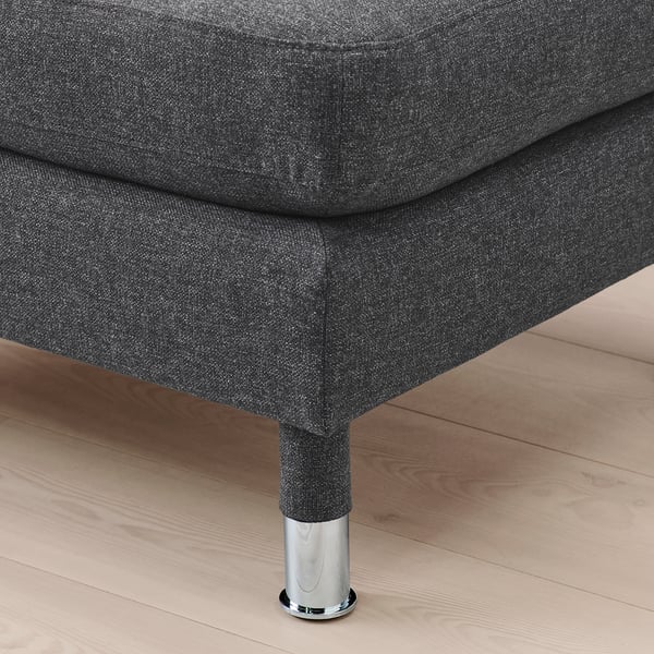 Dark grey fabric footstool with chrome legs on wooden floor.