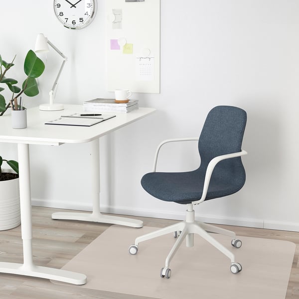 Home office setup: blue LÅNGFJÄLL chair, white desk, lamp, plants, clock, notes, books.