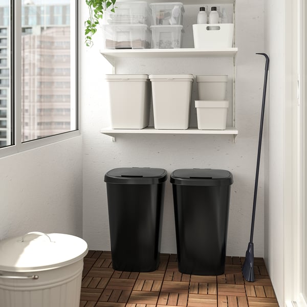 Storage area with two black bins, shelves, and cleaning supplies.