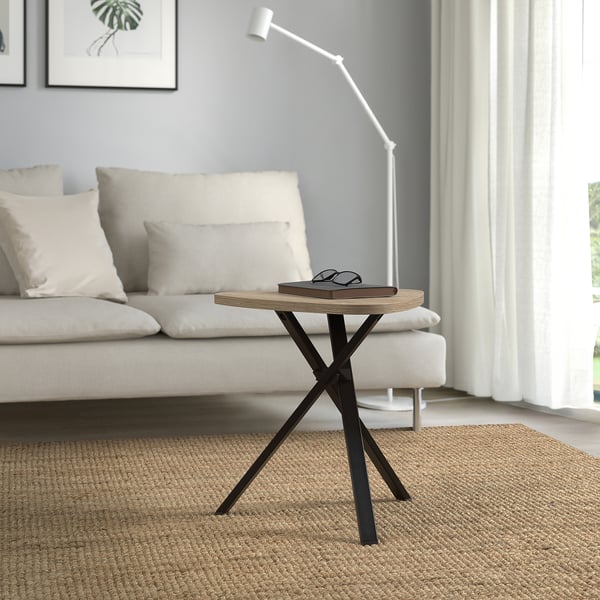Modern marriedamm side table with light wood top and dark metal legs beside white sofa.