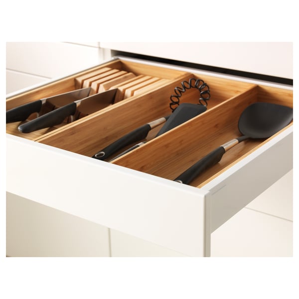 Open kitchen drawer with utensils: knives, whisk, spatula. Efficient storage.