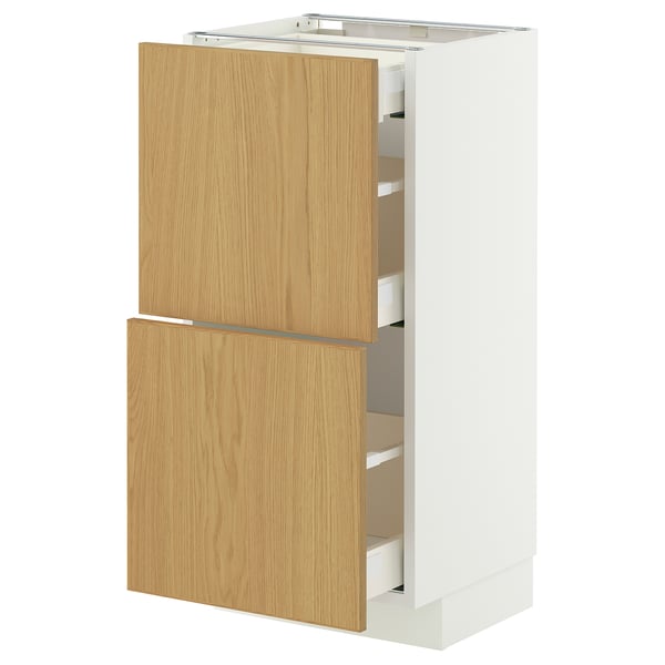 An IKEA METOD kitchen cabinet with light wooden doors and white sides. It includes multiple drawers and has a modern design.