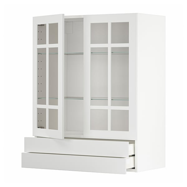 A white METOD kitchen cabinet with glass doors and drawers. It a modern, minimalist design with sleek lines and glass inserts.