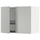 A white METOD kitchen wall cabinet with one door open, revealing a black wire shelf and a dish drainer.