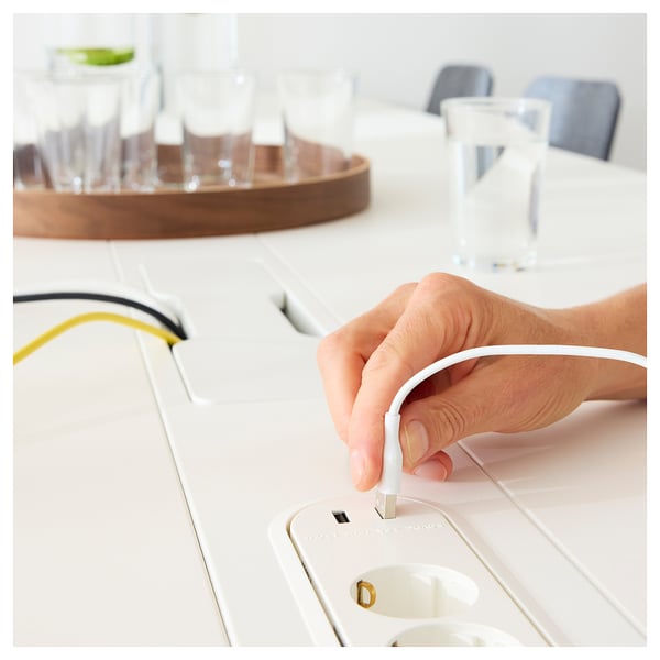 A hand adjusting a white cable management module on a high conference table.