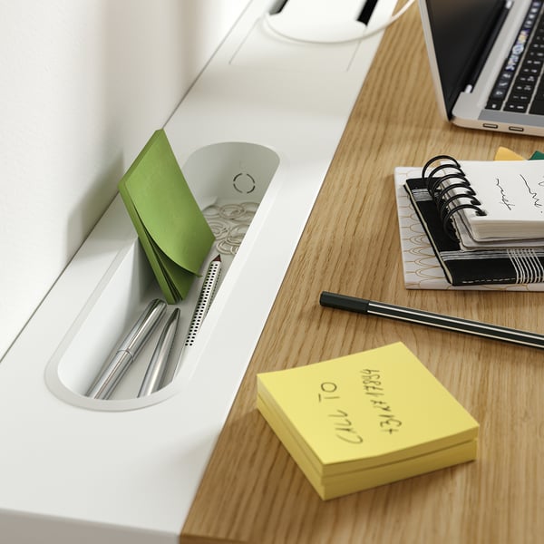 Wooden desk with pens, sticky notes, notebooks, and laptop. Includes a compartment for stationery and cable management tray.