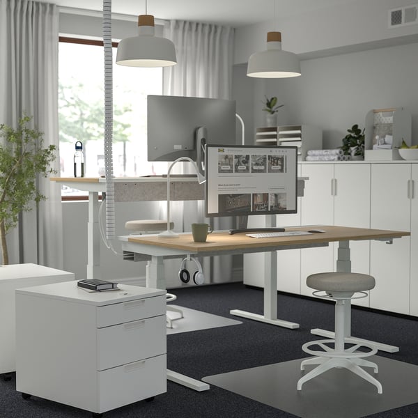 Minimalist home office with MITTZON desk, dual monitors, ergonomic stool, and storage.
