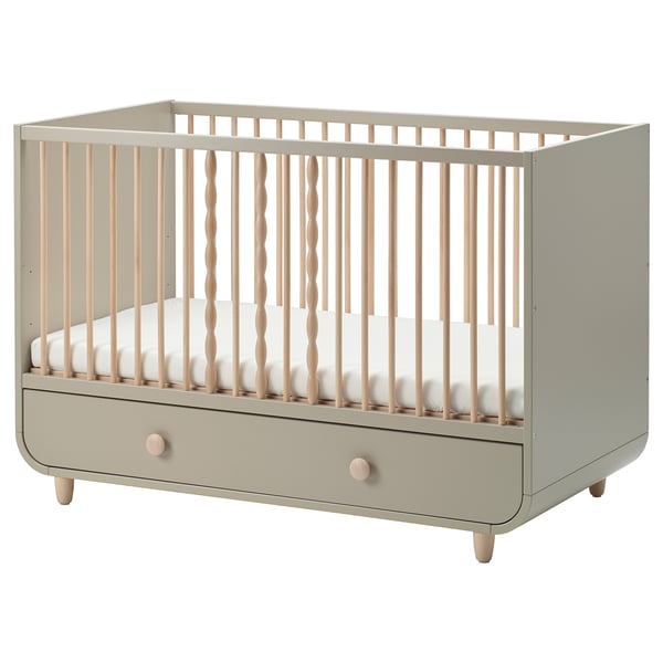 Modern beige MYLLRA crib with wooden spindles, adjustable height, and a storage drawer.