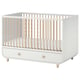 A white MYLLRA baby crib with natural wood accents, including adjustable sides and a bottom drawer for storage.