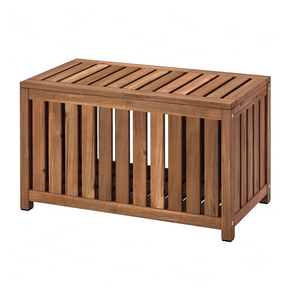 An outdoor NÄMMARÖ storage box made of brown acacia wood with a slatted design for ventilation and dual functionality as seating.