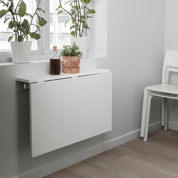 Fold-down wall table with plants and bottle on it.