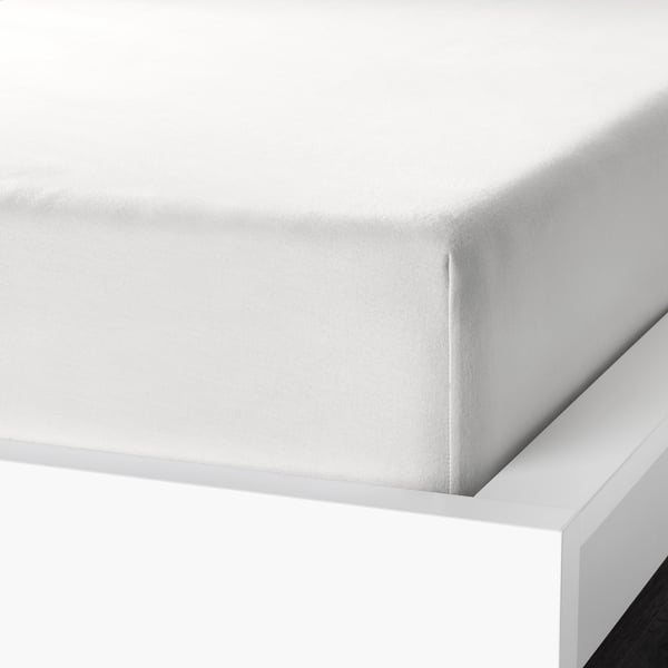 White bed sheet corner displayed, showcasing soft, velvety cotton flannel and elastic edging for secure fit.