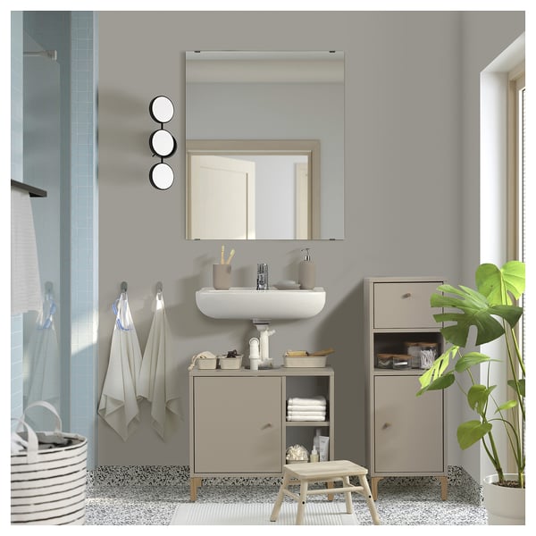 Modern bathroom with beige NORSÄLVEN cabinet, white sink, round mirrors, and green plant.