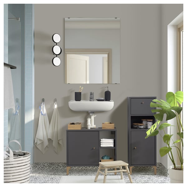 Modern grey bathroom cabinet with drawer and open shelves. Includes a white sink, mirror, towels, and plant.