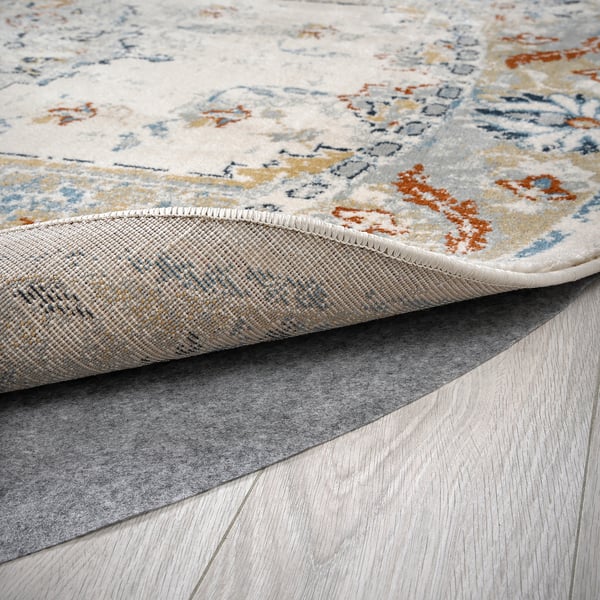 Close-up of a stylish, durable rug with faded patterns. Smooth pile and secure backing on wooden floor.
