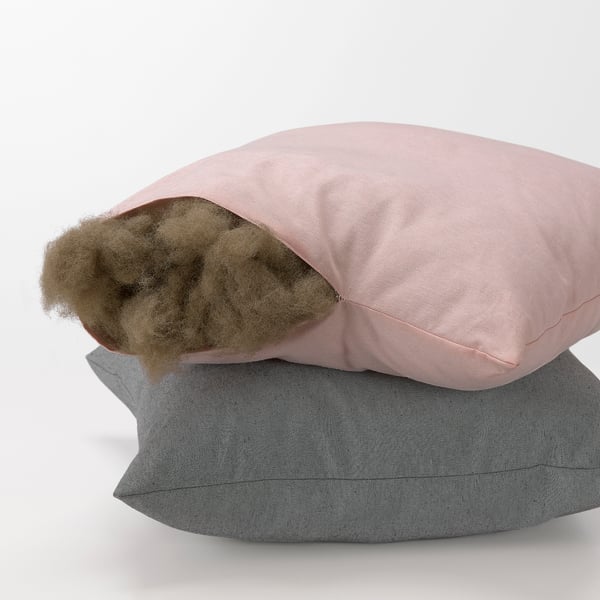 Stack of two pillows, top one open showing brown filler, soft, recycled materials.